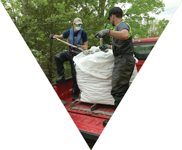 Two men in the back of a truck removing wetland ingredients