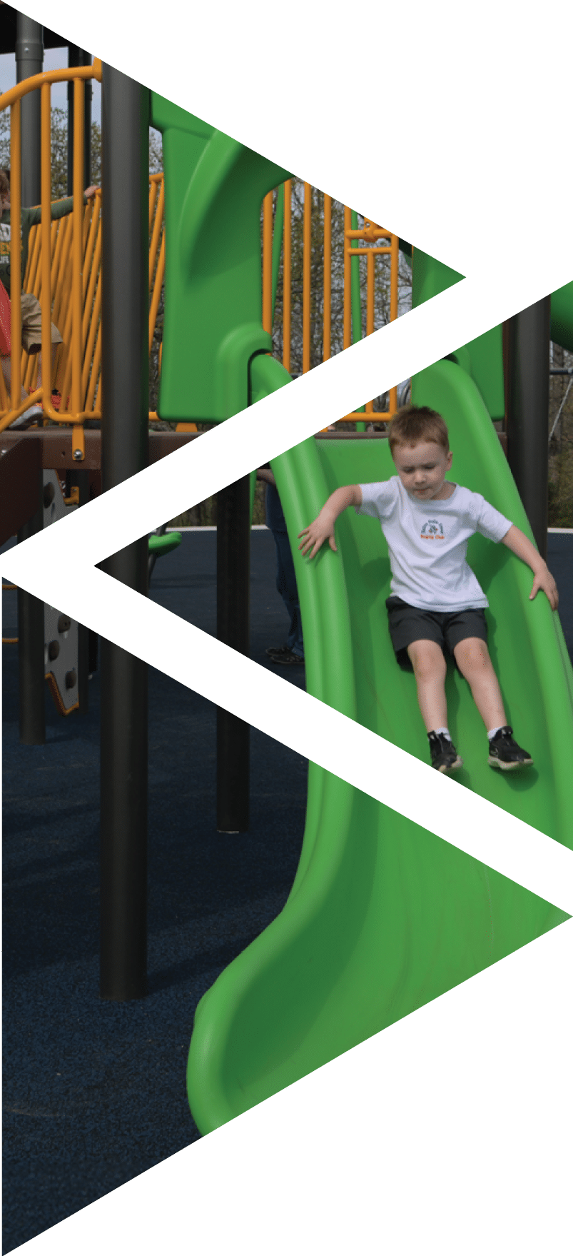 A young boy is playing on a green slide at Hatch playground.   